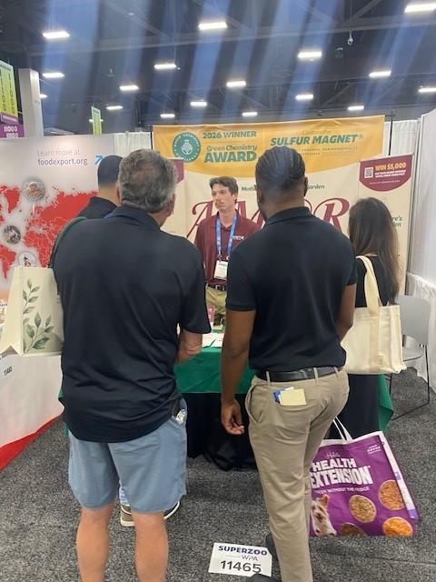 A member of the AMOR FELINE team in conversation with buyers at the booth counter