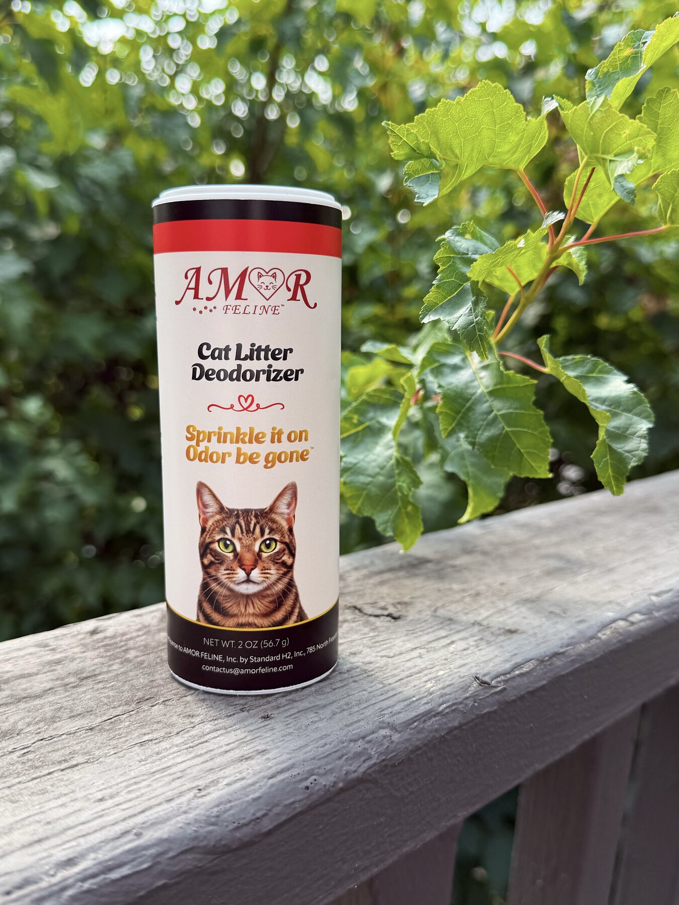 AMOR FELINE cat litter deodorizer outdoors among green leaves